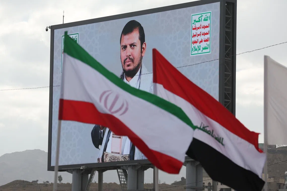 Iranian and Iraqi flags flutter in front of a billboard featuring Houthi leader Abdul-Malik al-Houthi during a protest in Sana'a, Yemen, on Nov 8.