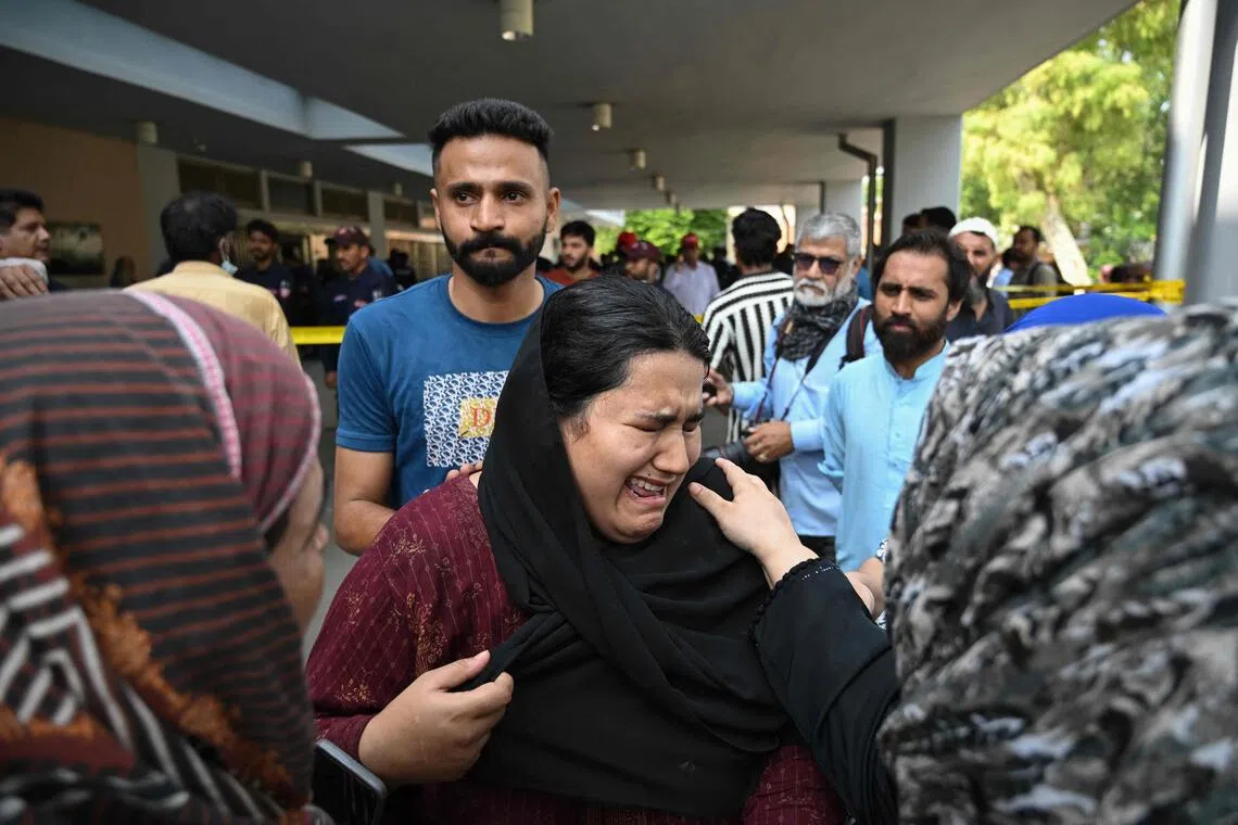 TOPSHOT - Jaweria (C), who said she lost her child in the fire, reacts following a blaze at the Mother and Child Health (MCH) ward of the Pakistan Institute of Medical Sciences (PIMS) Hospital in Islamabad on August 26, 2026. A fire in a maternity ward at a public hospital in the Pakistani capital Islamabad on August 26 morning killed 14 children, a local authority said. (Photo by Aamir QURESHI / AFP)