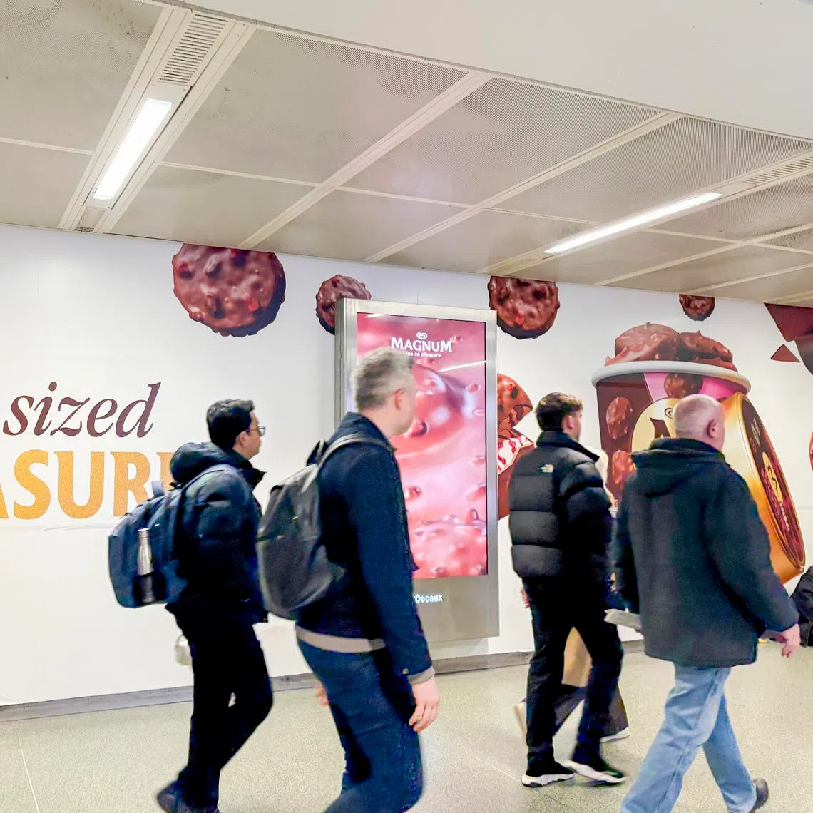 Commuters walk past a Magnum ad at King’s Cross Station in London on March 17.