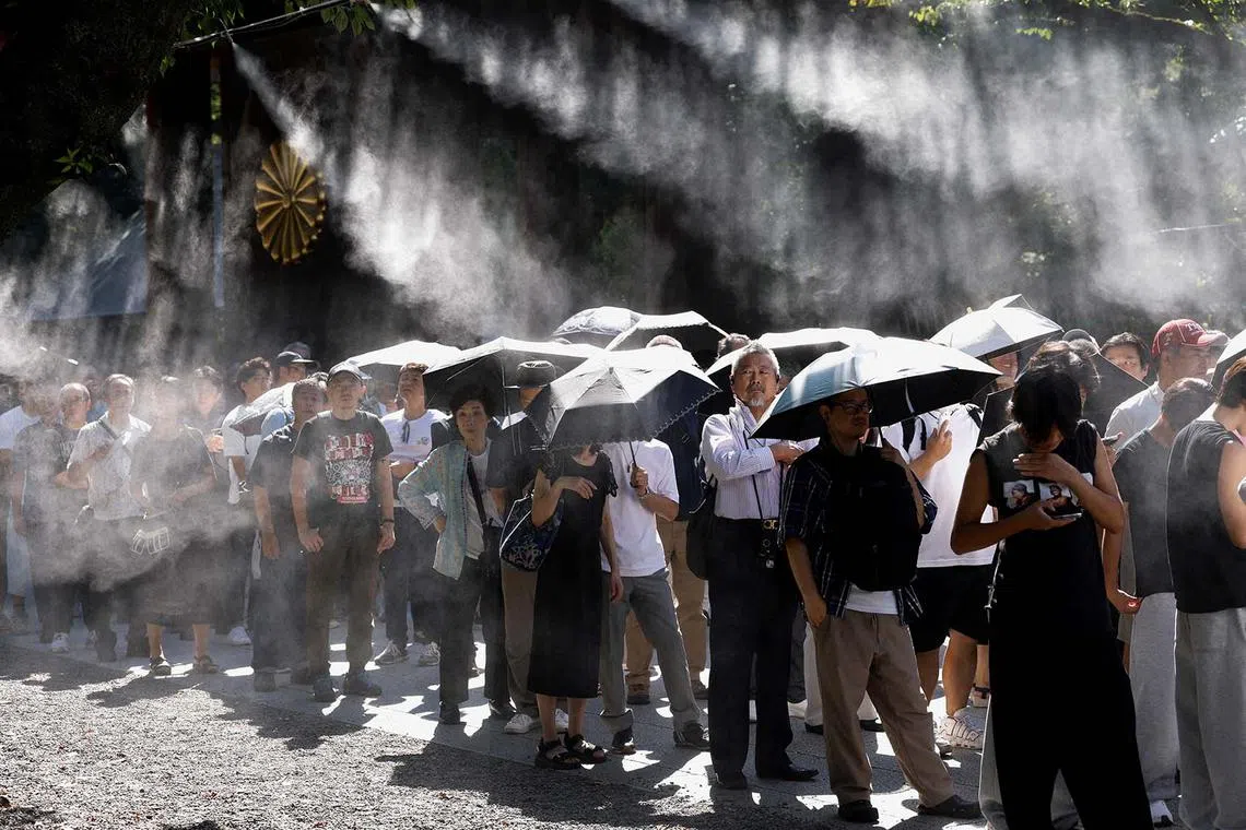 People standing in line, under umbrellas as mist is sprayed, to pray during their visit to the Yasukuni Shrine on the 80th anniversary of Japan's surrender in World War Two, in Tokyo, Japan, Aug 15, 2025. 