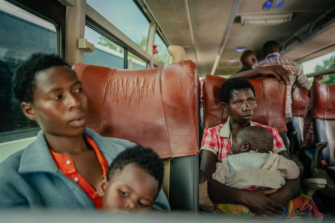 Two displaced persons, presumed to be Rwandan nationals, sitting in a large bus with their children after undergoing checks at the border, between the Democratic Republic of Congo and Rwanda, in Goma on May 19, 2025. They were transported in United Nations High Commissioner for Refugees (UNHCR) vehicles as part of their repatriation to Rwanda. 