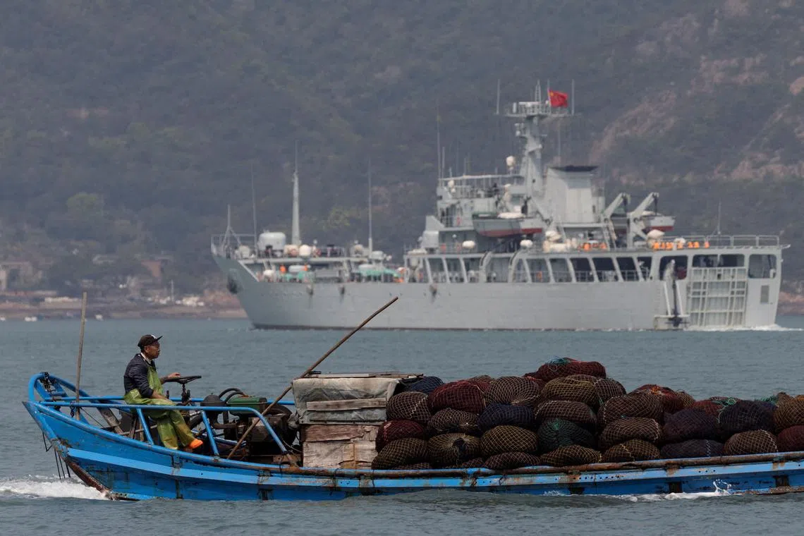 FILE PHOTO: A fishing boat sails past a Chinese warship during a military drill off the Chinese coast near Fuzhou, Fujian Province, across from the Taiwan-controlled Matsu Islands, China, April 11, 2023.  REUTERS/Thomas Peter/File Photo