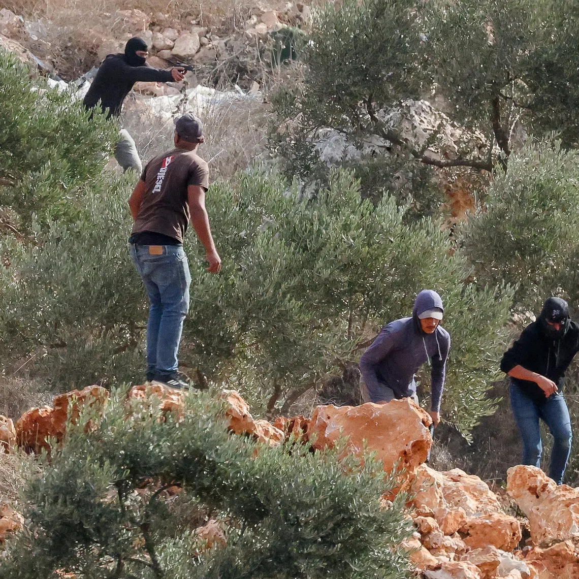 An Israeli settler points a gun amid clashes with Palestinians harvesting olives in Abu Falah near Ramallah in the Israeli-occupied West Bank, October 16, 2026. REUTERS/Ammar Awad