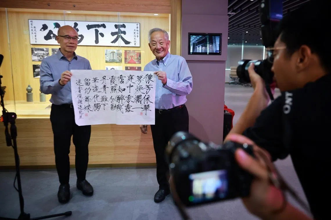 Mr Ng Kok Song (right) presenting a poem in calligraphy by his fiance Sybil Lau to Singapore Chinese Chamber of Commerce and Industry council member Charles Ho on Aug 14.
