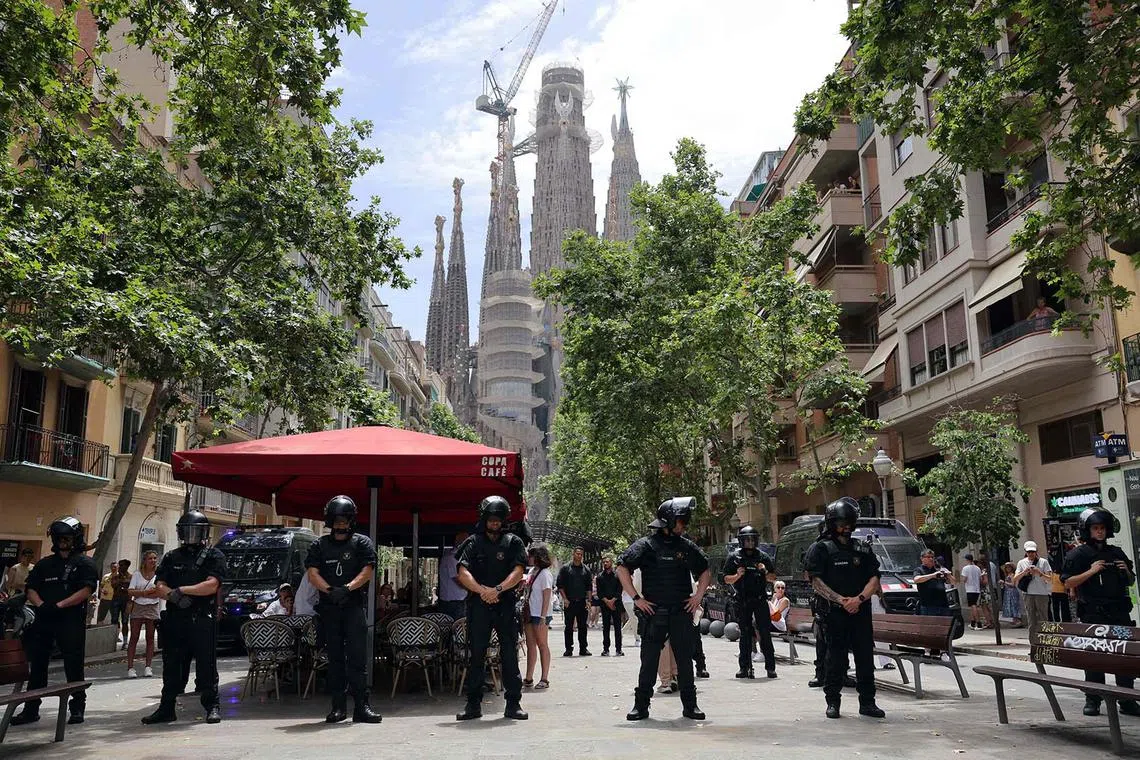 TOPSHOT - Catalan regional police officers (Mossos d'Esquadra) block protesters from advancing toward the Sagrada Familia Basilica during a demonstration against mass tourism in Barcelona, on June 15, 2025. (Photo by LLUIS GENE / AFP)