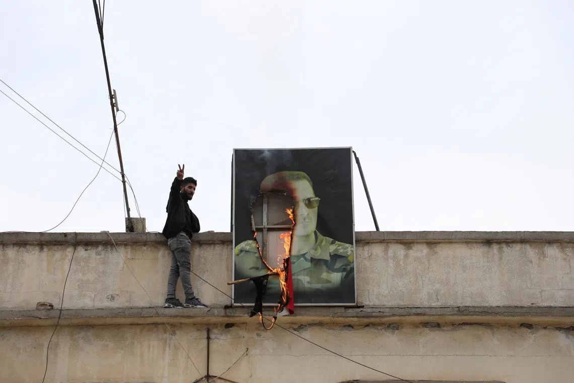 A person gestures next to a burning picture of President Bashar al-Assad, after rebels seized the capital and ousted the president, in Qamishli, Syria December 8, 2024. REUTERS/Orhan Qereman/File Photo