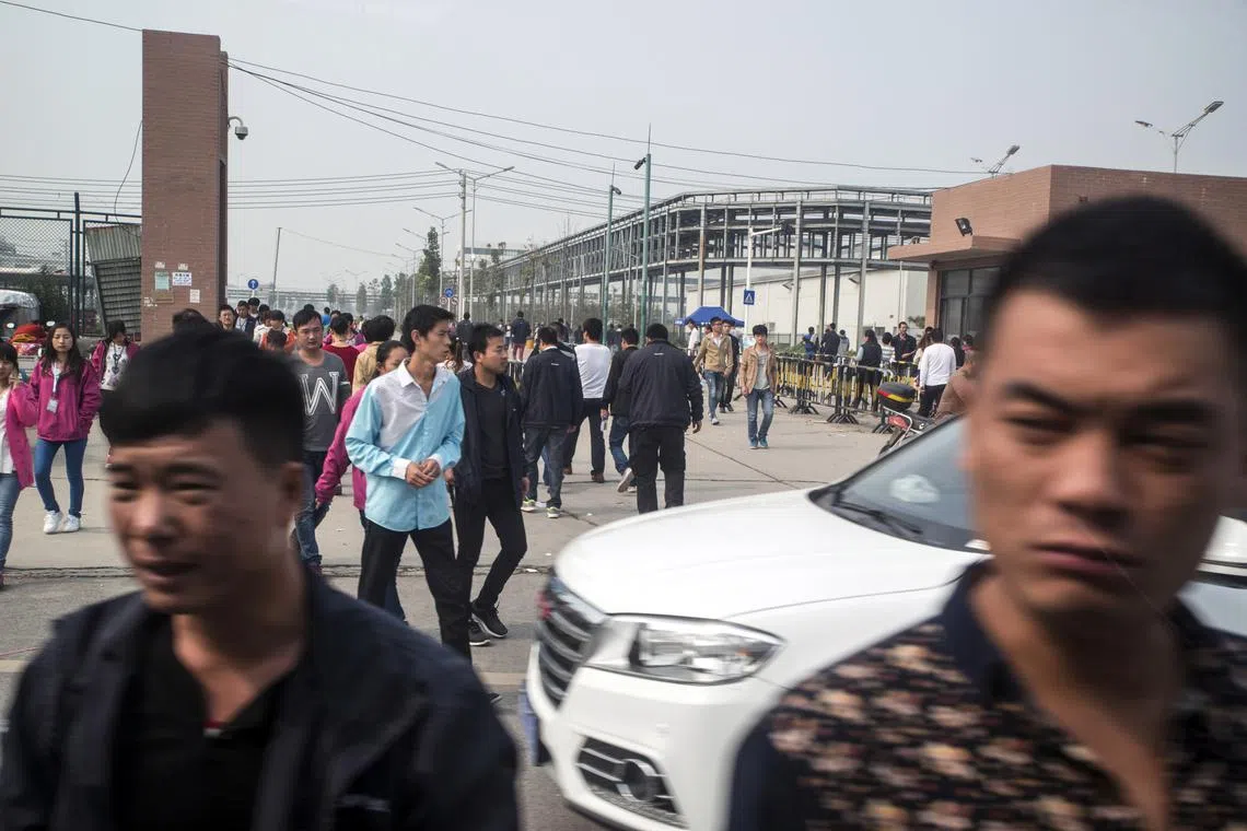 FILE PHOTO: Workers on their lunch break leave the Foxconn plant in Zhengzhou, China, on October 19, 2015. A COVID-19 outbreak in Zhengzhou has sent an unknown number of workers at the plant into quarantine. 