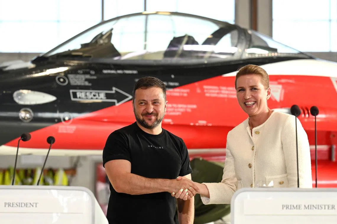 Ukrainian President Volodymyr Zelensky (L) and Danish Prime Minister Mette Frederiksen shake hands at a press confrence in front of a F-16 fighter jet in the hangar of the Skrydstrup Airbase in Vojens, northern Denmark, on August 20, 2023. Washington has told Denmark and the Netherlands that they will be permitted to hand over their F-16 fighter jets to Ukraine when the country's pilots are trained to operate them, the US State Department said on August 18, 2023. Both Denmark and the Netherlands are leading the program to train Ukraine's pilots on the F-16. (Photo by Sergei GAPON / AFP) / ALTERNATE CROP