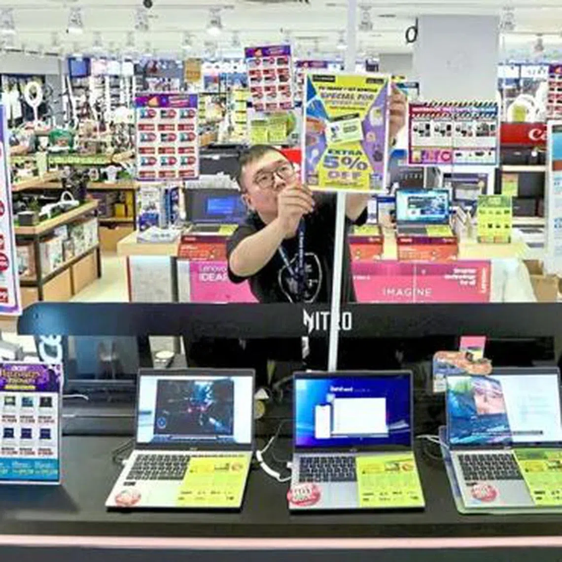 Worker adjusting 'sale' signs at an electronics shop in Komtar, Penang. 