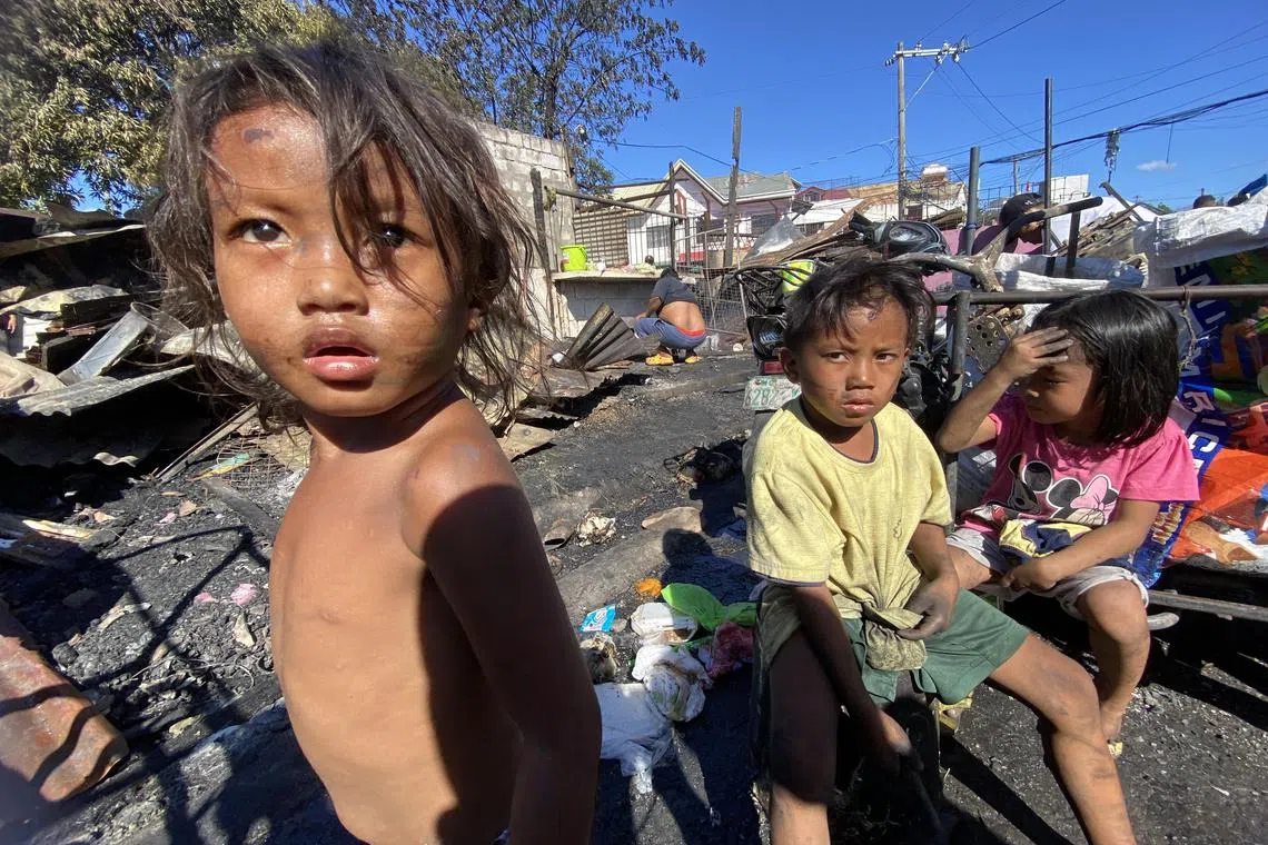 epa11255124 Children sit near damaged houses of a residential district following a fire in Las Pinas city, Metro Manila, Philippines, 02 April 2024. According to a report by the Philippines Bureau of Fire Protection (BFP), fire incidents between January and March are higher by 24 percent over the same period in 2023. Firefighters experienced a sharp increase in calls from households due to power overload and overheating of electric fans from non-stop usage, leading to fires.  EPA-EFE/FRANCIS R. MALASIG