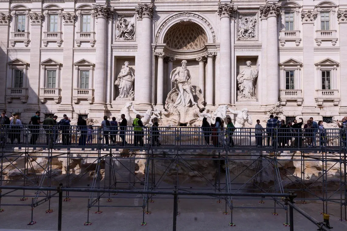 Tourists walk on an elevated walkway as Trevi Fountain undergoes maintenance work in Rome, Italy.

