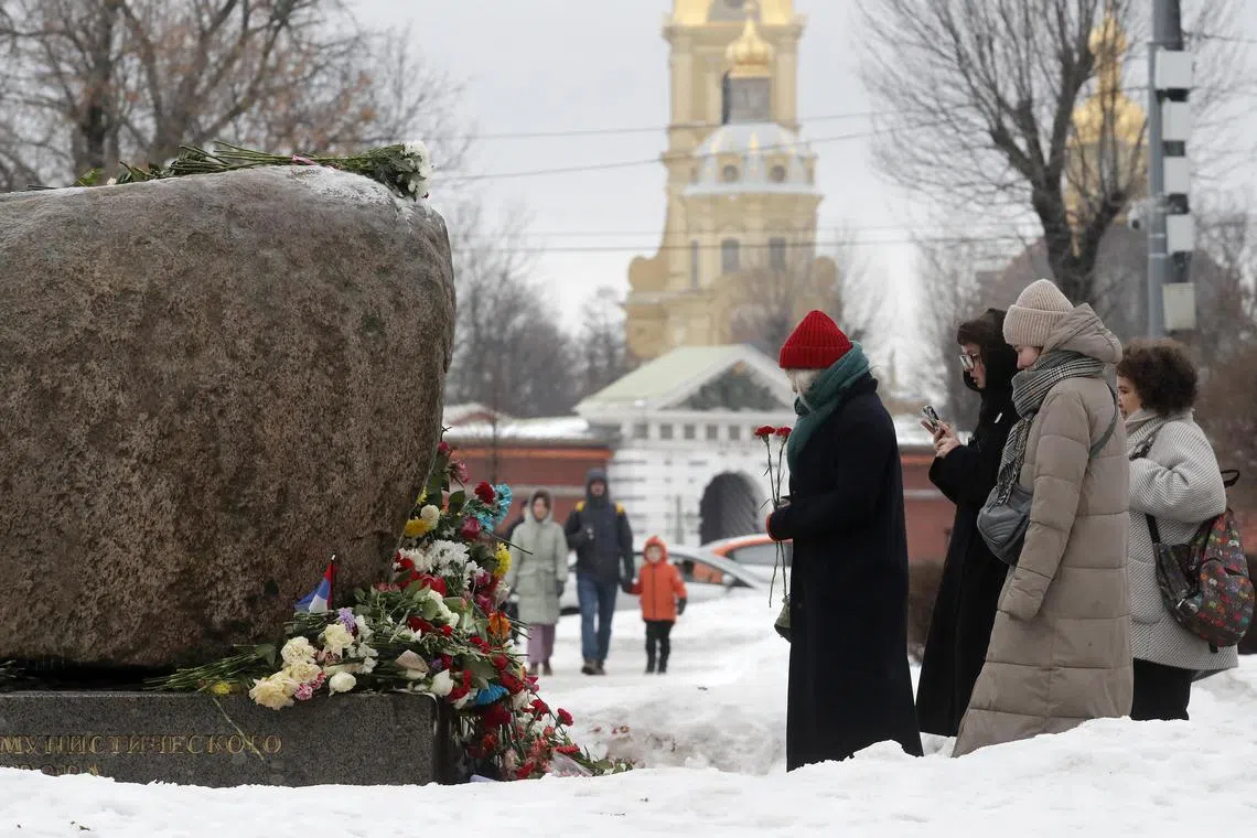 People lay flowers and light candles next to a photo of the late Russian opposition leader Alexey Navalny during a vigil in St Petersburg on Feb 16. 