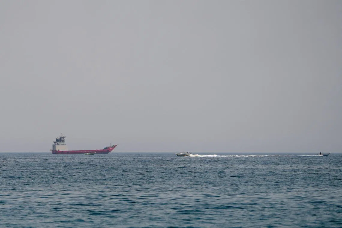 Several ships are visible on the open water under a gray sky.