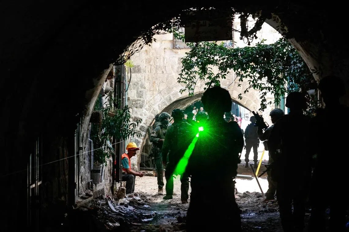 An Israeli soldier aiming his weapon fitted with a laser sight while patrolling the market in the Old City of Nablus in the northern Israeli-occupied West Bank on June 23.
