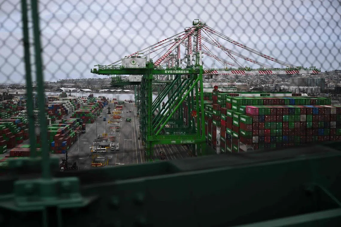 Cranes unload cargo shipping containers from the Evergreen Line Ever Mast container ship as seen from the Vincent Thomas bridge at the Port of Los Angeles in San Pedro, California on April 15, 2025. US President Donald Trump ordered a probe April 15, 2025 that may result in tariffs on critical minerals, rare-earth metals and associated products such as smartphones, in an escalation of his dispute with global trade partners. China said April 16, 2025 its economy topped forecasts in the first quarter, as exporters rushed to shift goods ahead of swingeing US tariffs, but warned it faced "certain pressures" from Donald Trump's trade blitz. (Photo by Patrick T. Fallon / AFP)