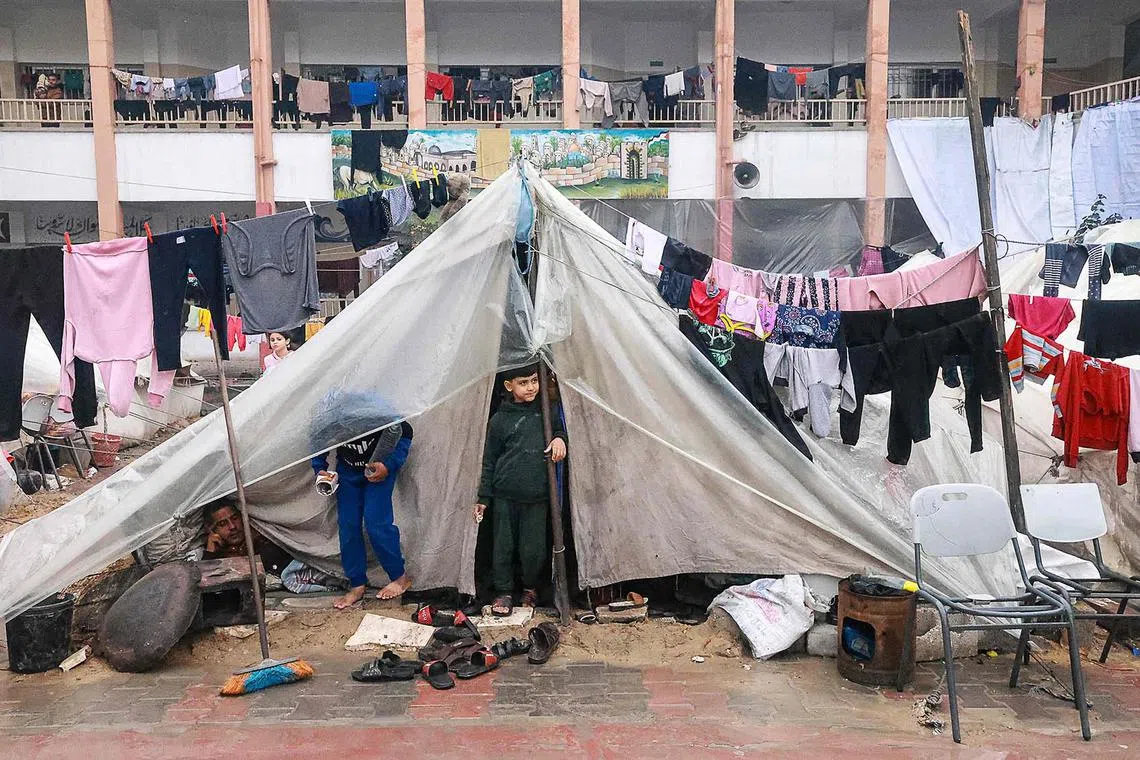 Palestinian boys standing in their makeshift tent at a camp set up on a schoolyard in Rafah in the southern Gaza Strip where most civilians have taken refuge, on Dec 13, 2023, as battles continue between Israel and the Palestinian militant group Hamas. 