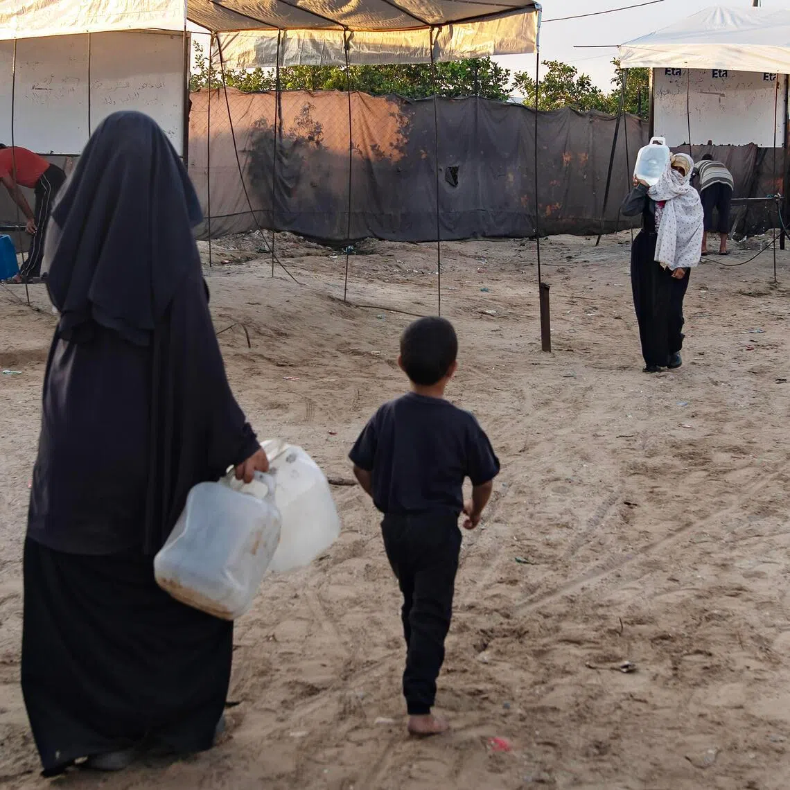 Displaced Palestinians collect water from the Ita charitable water station in Khan Younis, Gaza Strip, on July 13.