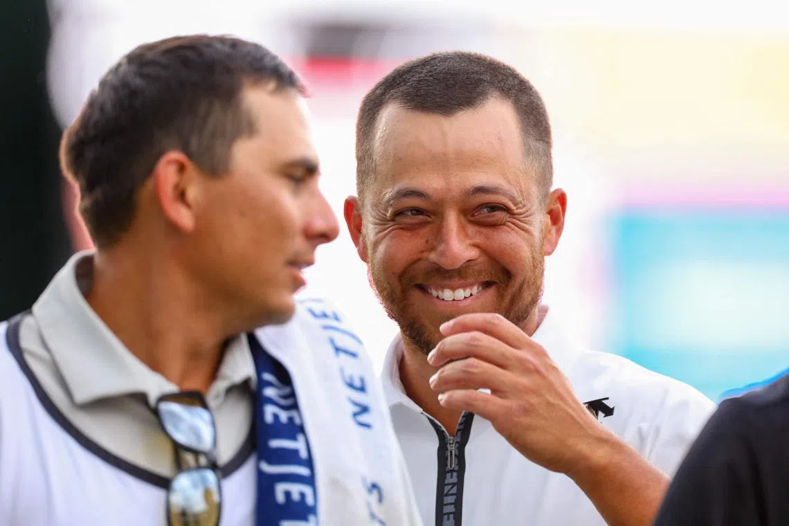 Xander Schauffele laughs with his caddie Austin Kaiser as they walk off the 18th hole after finishing the second round of the Wells Fargo Championship at Quail Hollow Country Club on May 10, 2024.