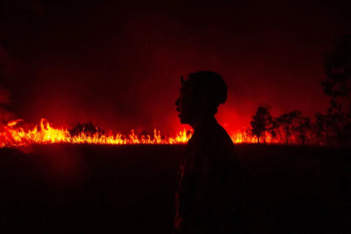 A firefighter reacts as they attempt to extinguish a wildfire in Ogan Ilir, South Sumatra, on September 14, 2023. The 2023 United Nations Climate Change Conference COP28 will be held from November 30 to December 12, 2023, in Dubai. (Photo by Al ZULKIFLI / AFP)
