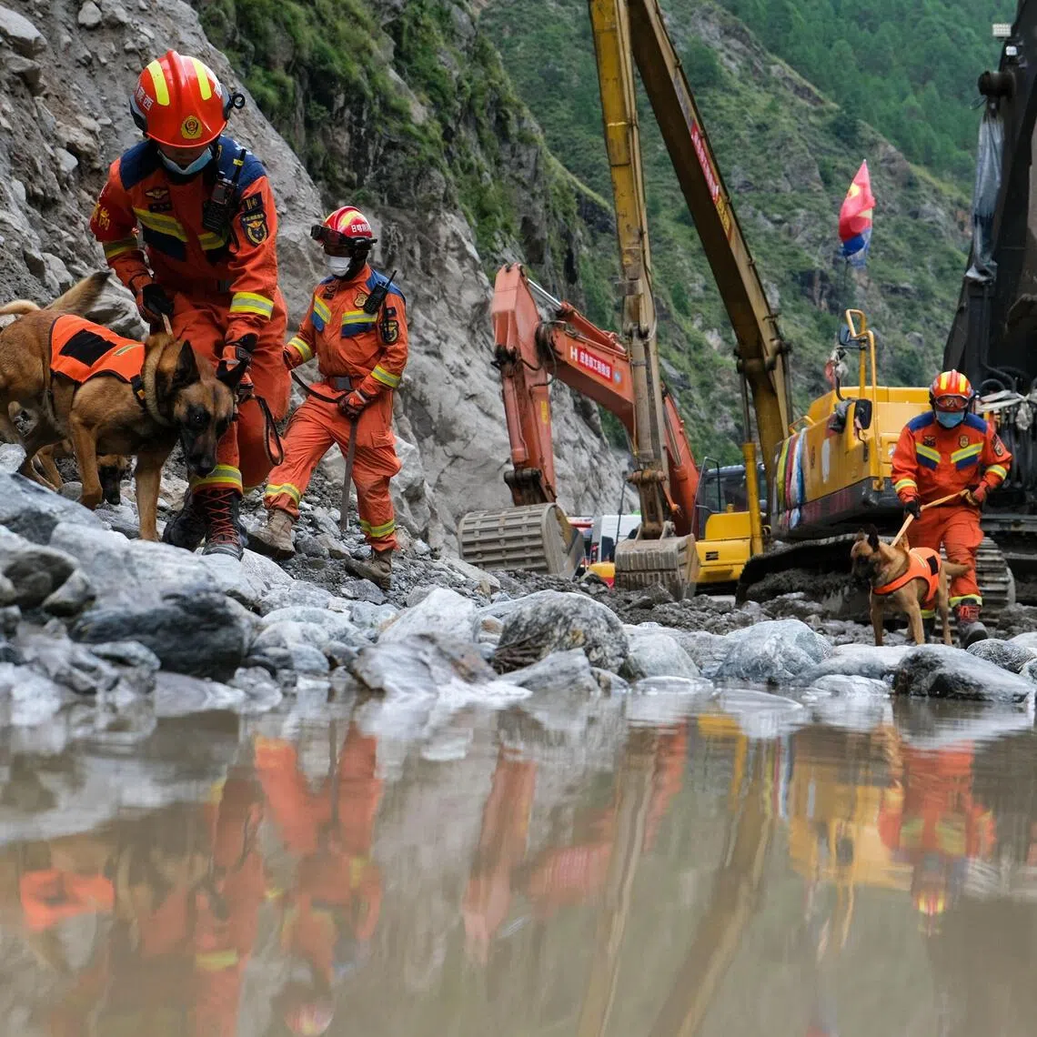 Fire and rescue personnel use dogs to search for victims of a mudslide beside the road which leads to Gyirong Port in China’s western Tibet.