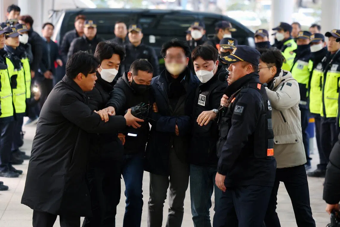 A man (centre, with face blurred) being taken away by police in Busan, South Korea, on Jan 2, 2023.
