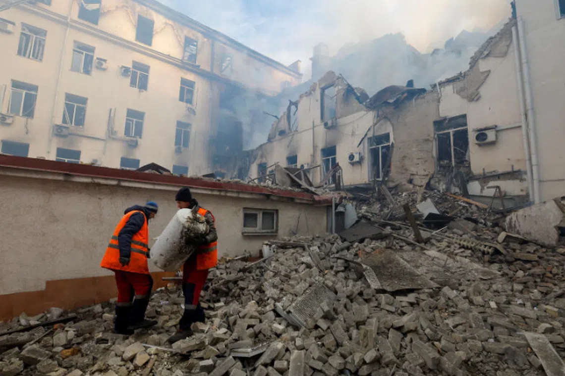 Municipal workers remove debris outside a local railway building damaged in shelling in Donetsk, Russian-controlled Ukraine, 
