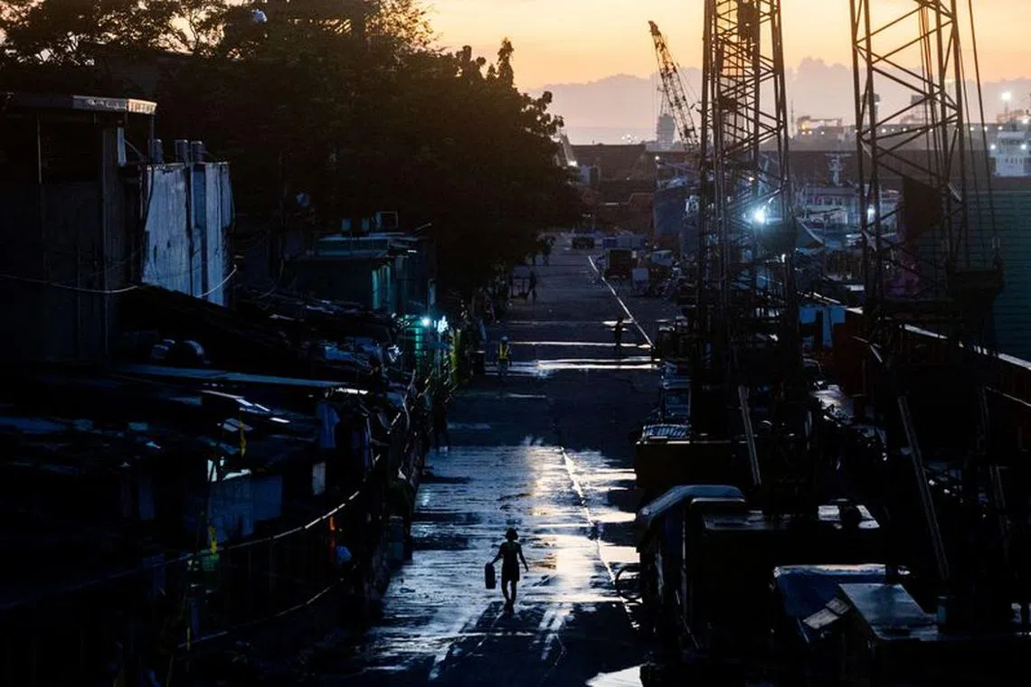 A woman carries a water container near the port area in Manila, Philippines, October 24, 2022. REUTERS/Lisa Marie David/File Photo