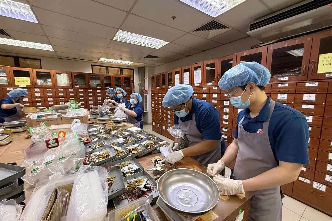 Traditional Chinese medicine practitioners preparing herbal remedies at Kuala Lumpur's Tung Shin Hospital.