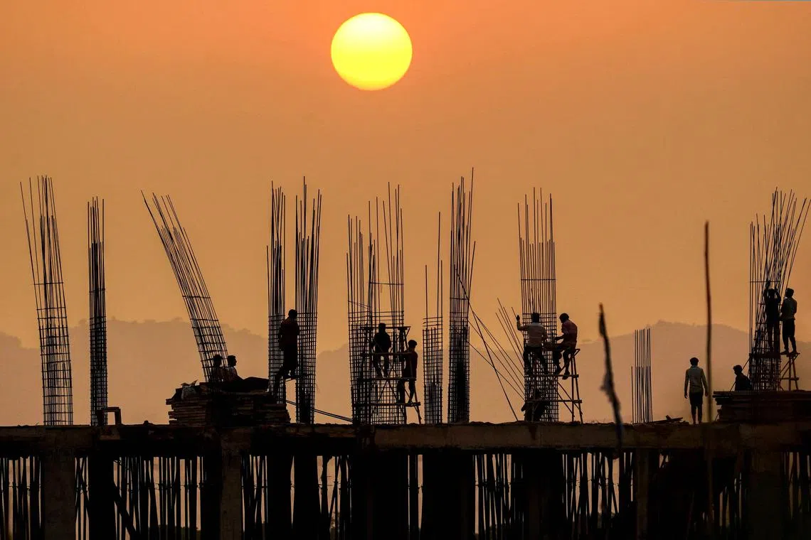 Workers are silhouetted against the setting sun at a construction site in Pushkar, India.