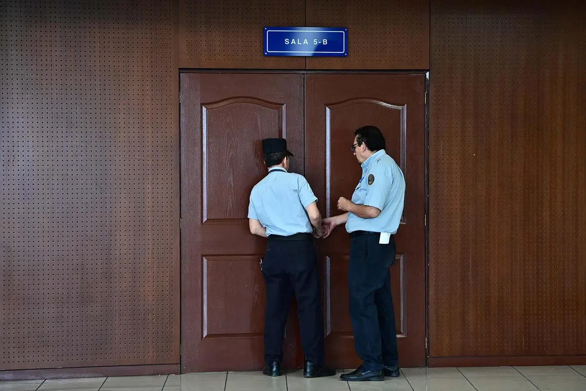 TOPSHOT - Security officers guard a door during a hearing against 11 officers, including former Salvadoran President Alfredo Cristiani, at the Isidro Menendez Judicial Center in San Salvador on November 13, 2024, during a trial for the murder of six Jesuit priests in 1989. Six Spanish Jesuit priests and two employees were murdered by government military forces on November 16, 1989, during a guerrilla offensive on the Salvadorian civil war from 1979 to 1992. (Photo by MARVIN Recinos / AFP)