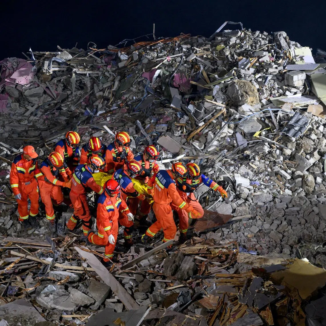 Rescue workers carry a casualty as they search for survivors at the site of a landslide along the Wujiang river in Chongqing.