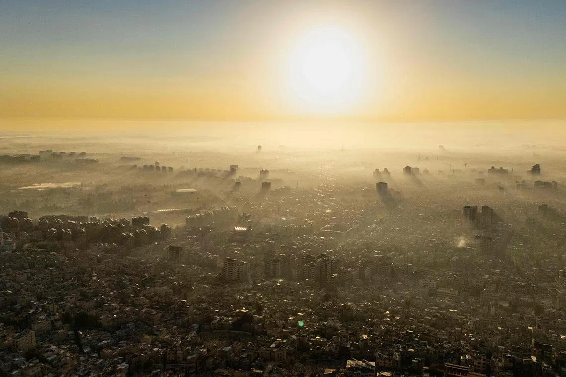 TOPSHOT - A picture taken from Mount Qasioun shows the sun rising as a thick fog covers Damascus on December 25, 2024. (Photo by Sameer Al-DOUMY / AFP)