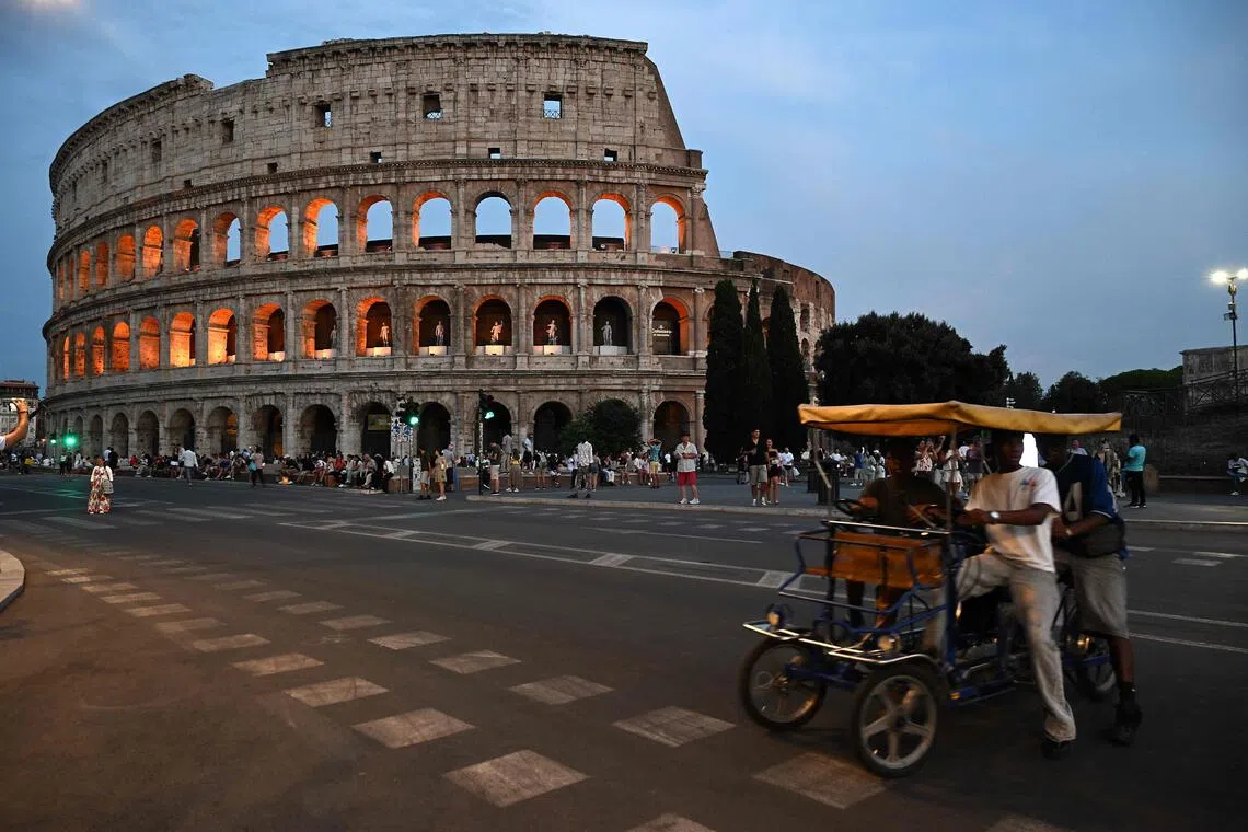 Pedestrians walk past the Rome’s ancient Colosseum during “A Night at the Colosseum” tour, a guided visit.