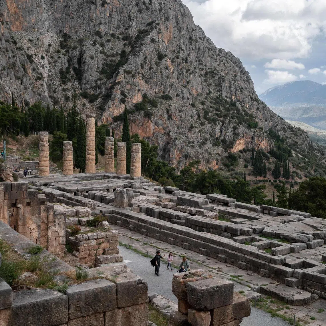 (FILES) Pedestrians visit the archaeological site of Delphi, a UNESCO World Heritage site, in Delphi, on November 17, 2022, amid a conference marking the 50th anniversary of the UNESCO World Heritage Convention. From 2022 to 2025, scientists at the National University of Athens and the National Hellenic Research Foundation examined past and present climate and geological conditions at the 19 sites, looking at prior damage to help determine future vulnerability to extreme events. The sites under scrutiny include Olympia, habitually threatened by forest fires, the ancient theatre of Delphi, where rockslides are a concern. (Photo by Angelos Tzortzinis / AFP)