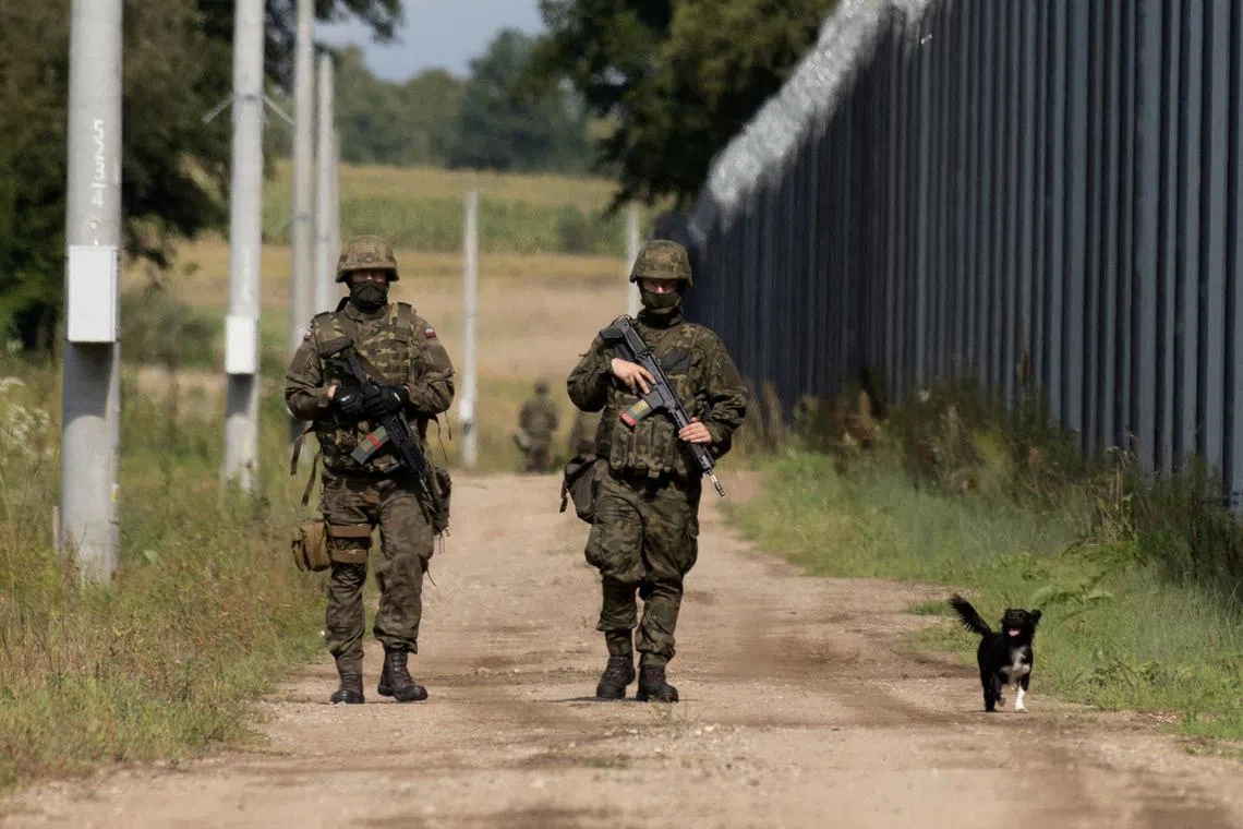 FILE PHOTO: Polish soldiers and a local dog walk along the border fence on the Polish-Belarusian border in Usnarz Gorny, Poland, August 30, 2023. REUTERS/Kuba Stezycki/File Photo