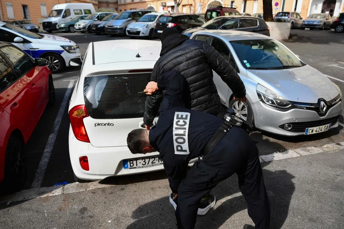 A police officer checks a suspected dealer for drugs in a northern district of Marseille, southern France.