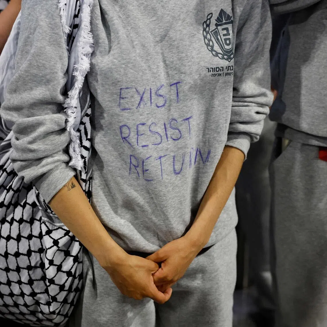A French activist detained and deported by Israel following the interception of their Gaza-bound flotilla wearing a sweat shirt with written "Exist, resist, return".