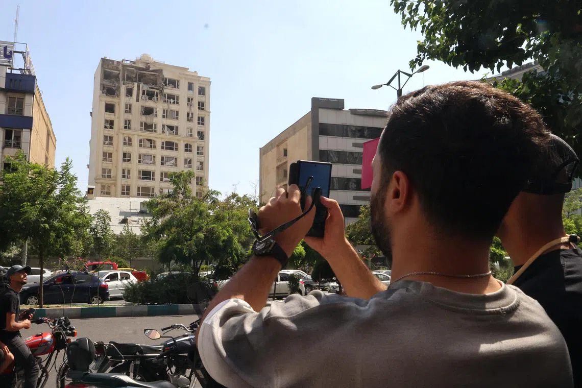 A man taking a picture of a building damaged by an Israeli strike on Tehran, on June 13.