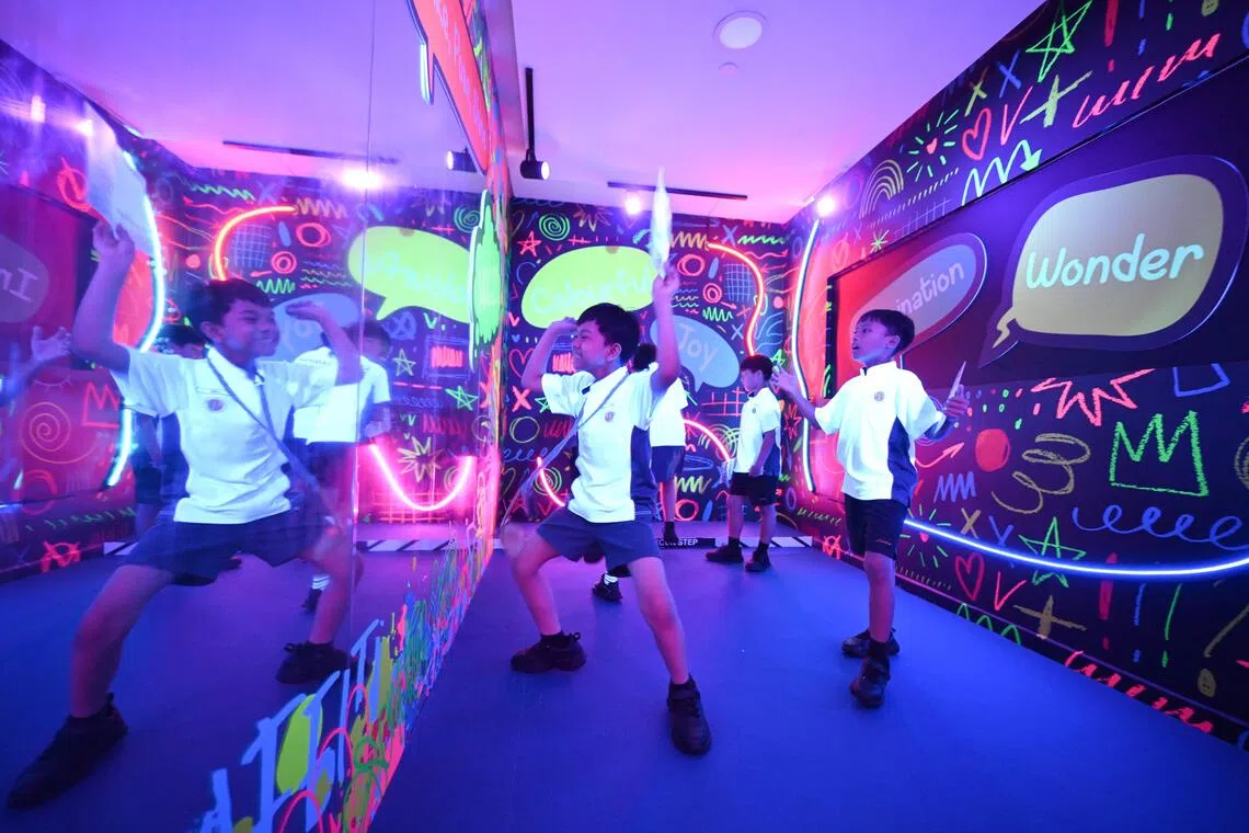 Langit, 10 (left), and Mizanul, 11, dancing in front of a full-length mirror surrounded by playful pop-up words and neon lights at Reflections of Neon.