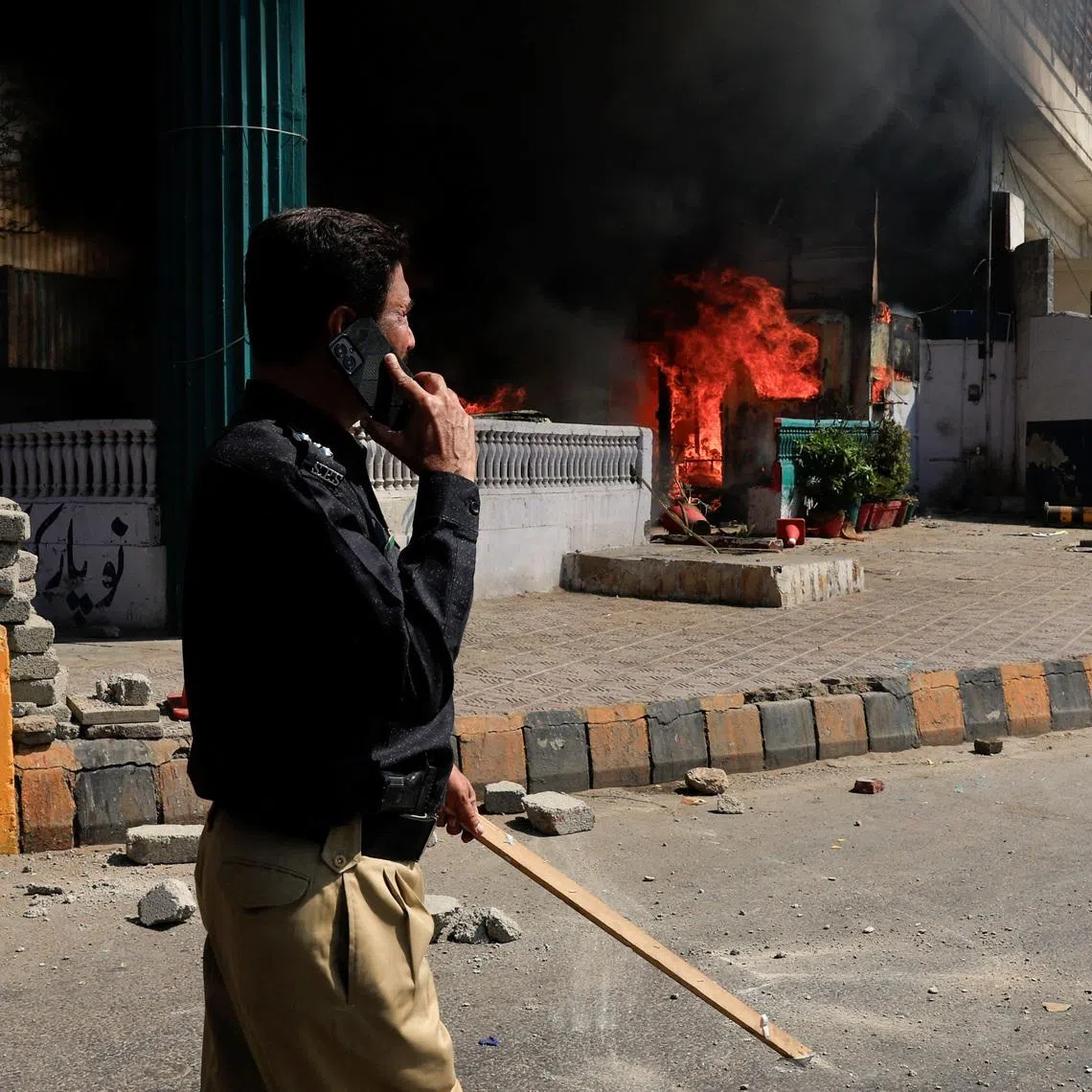 A police officer walks next to a checkpost set ablaze in a protest outside the U.S. Consulate General, following news of U.S. and Israeli strikes on Iran that killed supreme leader Ayatollah Ali Khamenei, in Karachi, Pakistan March 1, 2026. REUTERS/Akhtar Soomro