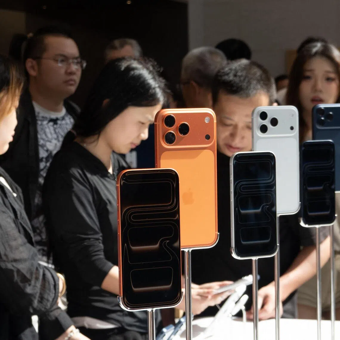 People check the new iPhone 17 lineup at an Apple store in Shanghai on September 19, 2025.