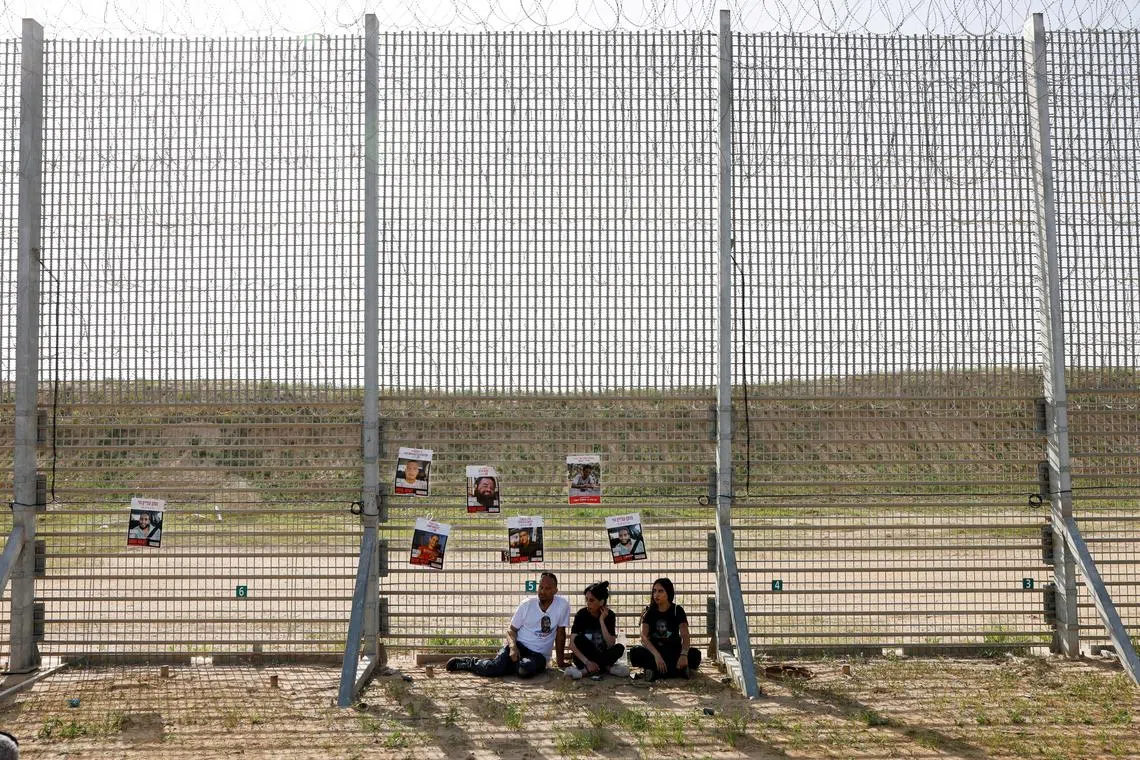 The family of hostage Matan Zangauker, who was kidnapped during the deadly October 7, 2023, attack on Israel by Hamas, sitting as posters of hostages hang from the Israel-Gaza border fence, in Israel, on March 18, 2025. 