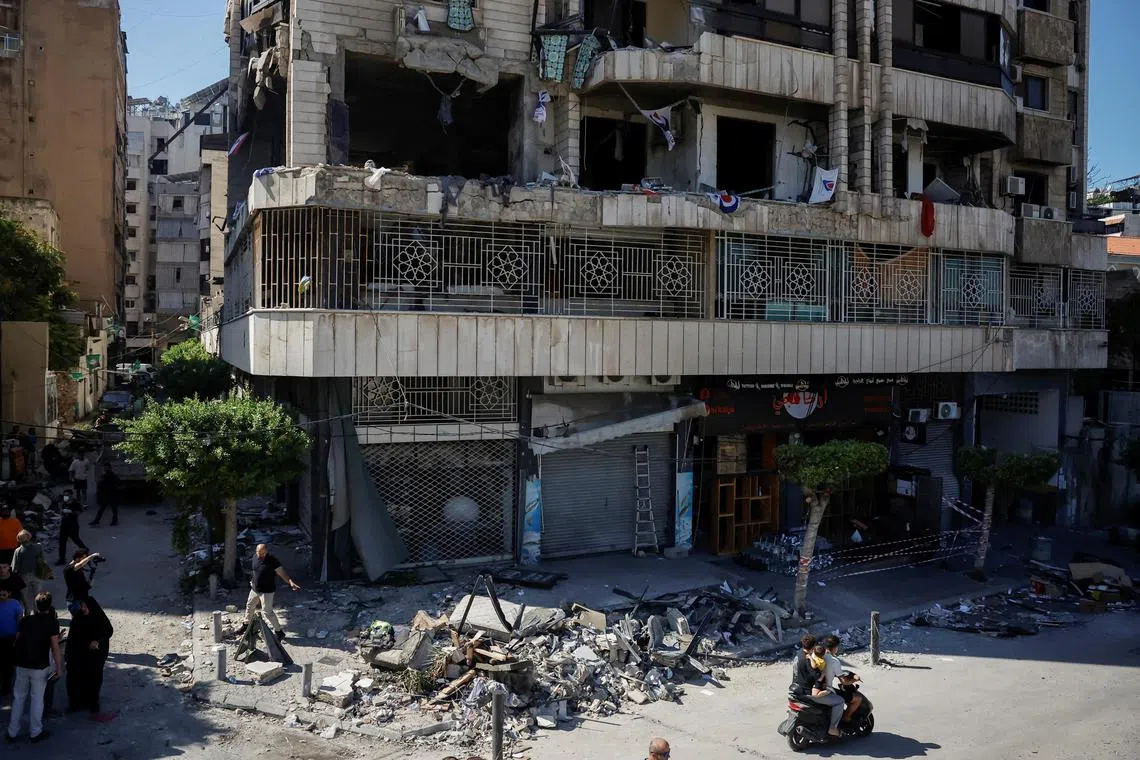 People walking past a building in central Beirut which housed the Islamic Health Organisation and which was damaged by an Israeli strike, on Oct 3.