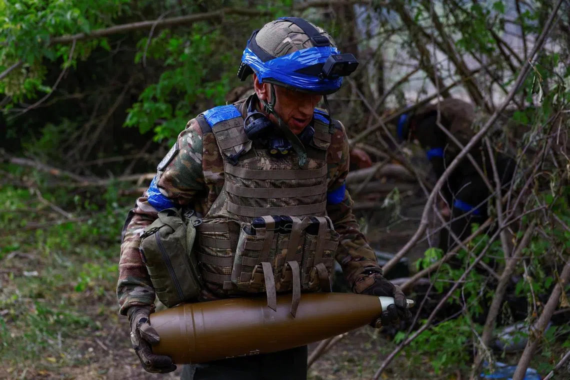 A Ukrainian serviceman carrying a 152mm shell for firing at Russian front-line positions in Ukraine's Kharkiv region, on May 21.