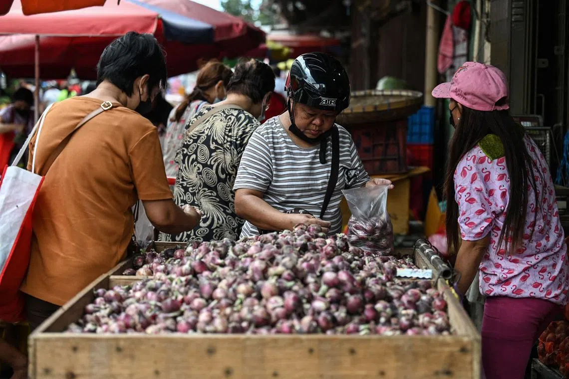 Customers shopping for onions at a market in Manila on Jan 19, 2023.