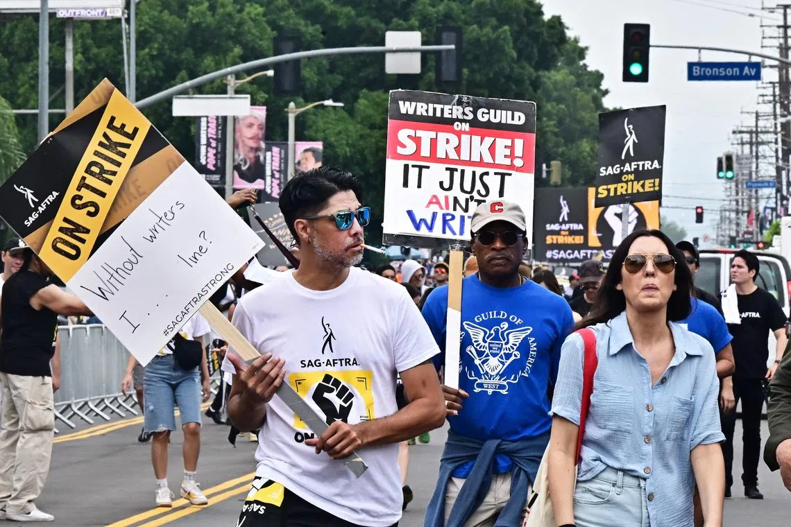 Strikers carry signs as writers and actors staged a solidarity march through Hollywood to Paramount Studios on September 13, 2023 amid a halt in movie and TV production as the dual labor shortages continue. The Writers Guild of America has been on strike since early May and the
SAG-AFTRA actors' union joined the writers on the picket lines in July. (Photo by Frederic J. BROWN / AFP)