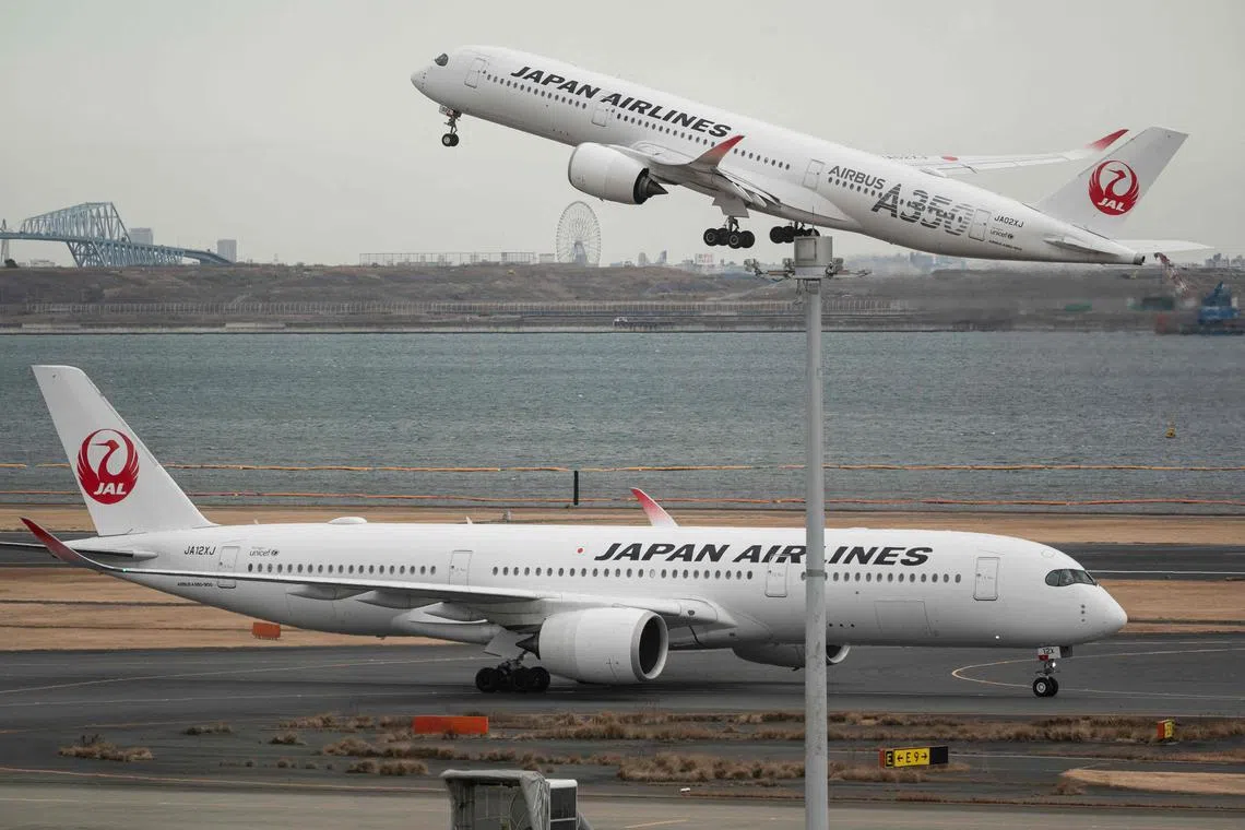 A passenger jet from Japanese carrier Japan Airlines (JAL) takes off past another at Tokyo International Airport at Haneda on February 2, 2023. (Photo by Richard A. Brooks / AFP)