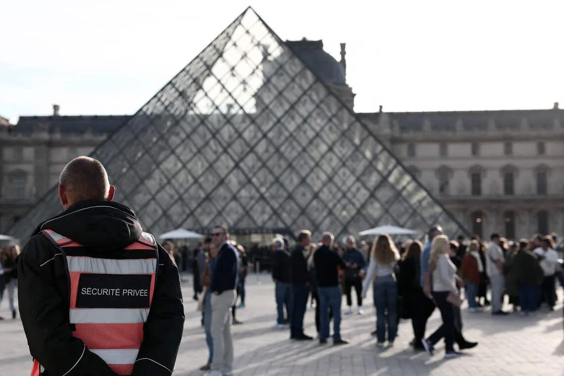 A security guard wearing a vest stands in front of the Louvre Museum in Paris on Oct 22.