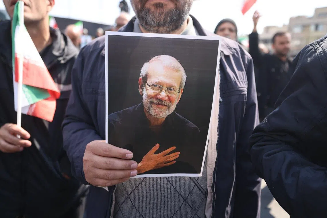 A mourner holds a picture of Iran's security chief Ali Larijani during his funeral, in Tehran, on March 18, 2026.