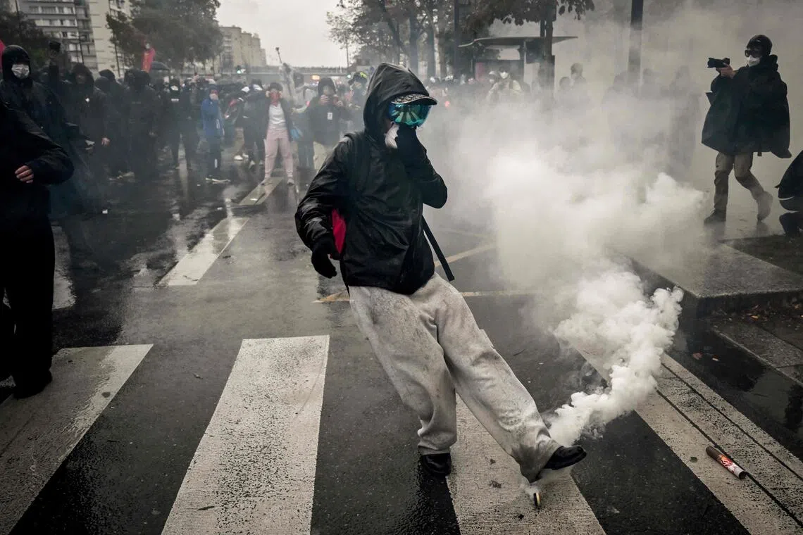 A person kicking a tear gas canister in Paris on Oct 24. Riot police fired tear gas and water cannon to disperse a group of around 500 hooded youths who hurled stones at officers.